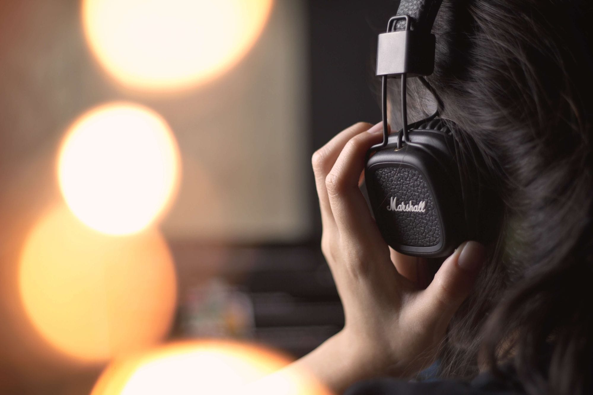  A woman listens to music on headphones, illustrating finding trending sounds on TikTok